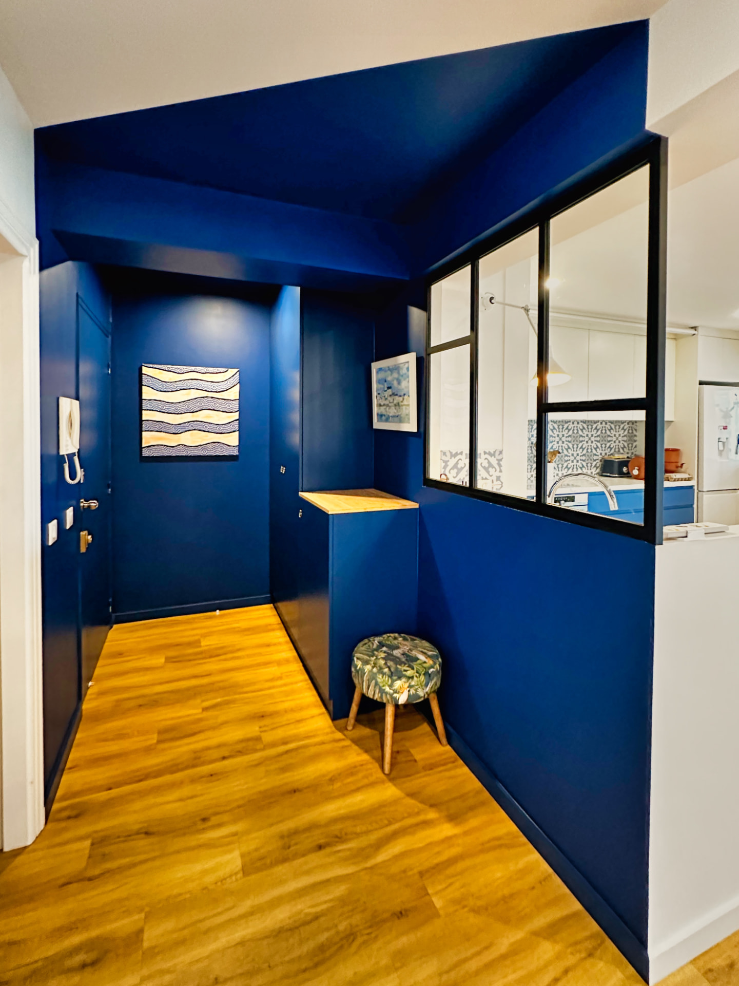 Entrée peinte en bleu profond avec parquet et verrière noire